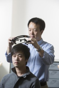 Brainprint: Zhanpeng Jin, assistant professor of Electrical and Computer Engineering and Biomedical Engineering uses an electroencephalogram headset to measure electrical signals within the brain, on Binghamton doctoral student Borui Li. (Jonathan Cohen, Binghamton University photographer)