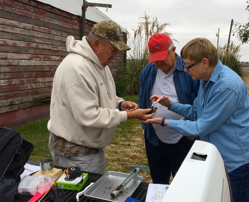 Volunteers standing outside feeling the texture of dirt collected as part of the MO Dirt program.