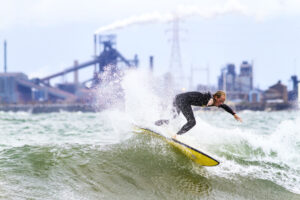 Surfers: A surfer rides a wave against the industrial backdrop of Lake Michigan. (Credit: Mike Killion/Courtesy of Surfrider)