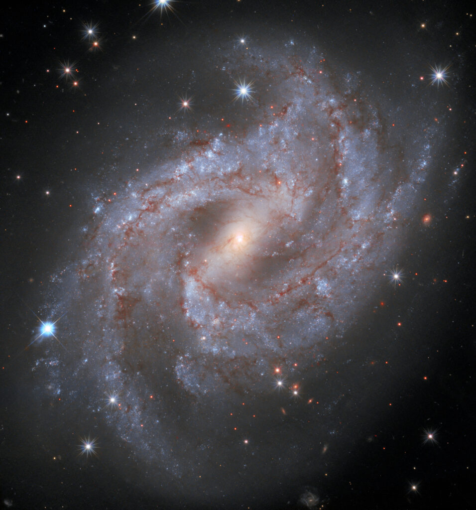 Where do heavy elements come from? Supernova SN 2018gv, appears in the lower left portion of the frame as a blazing star located on the outer edge of spiral galaxy NGC 2525, located 70 million light-years away. At its peak SN 2018gv was as bright as 5 billion Suns. Credits: NASA, ESA, and A. Riess (STScI/JHU) and the SH0ES team; acknowledgment: M. Zamani (ESA/Hubble)