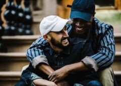 Two men of color cuddle on a home's front steps. Favorite Songs Link Up to Attachment Styles.