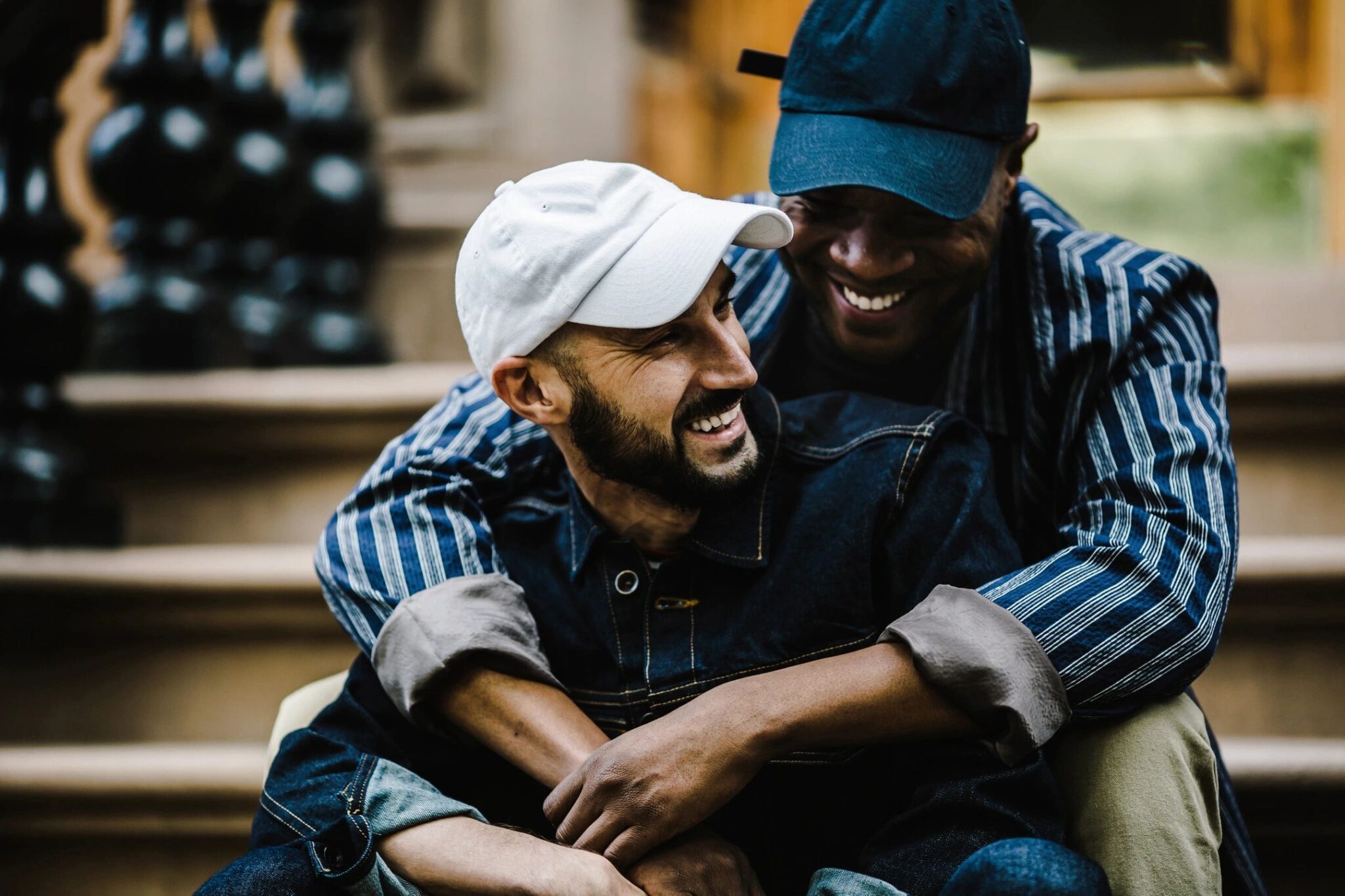 Two men of color cuddle on a home's front steps. Favorite Songs Link Up to Attachment Styles.