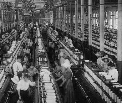 Black and white photo of people working on an assembly line in a factory. Image credit: Living with Machines 