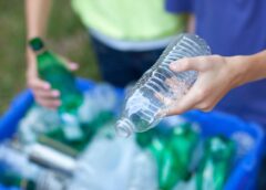 People putting plastic bottles in recycling bin.