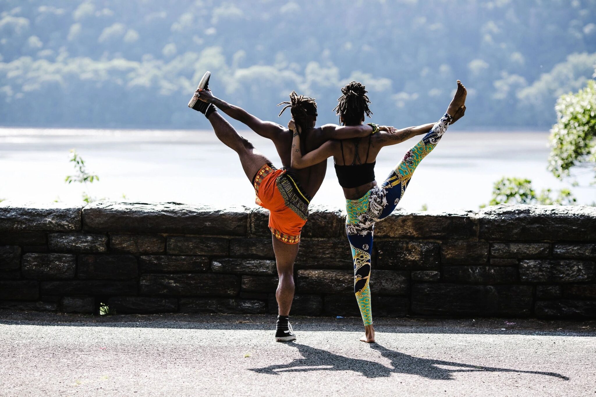 matching up enzymes in Alzheimer’s Research is symbolically represented here by two people linking arms while they each use their free hand to lift a leg high up in the air, forming a combined Y shape