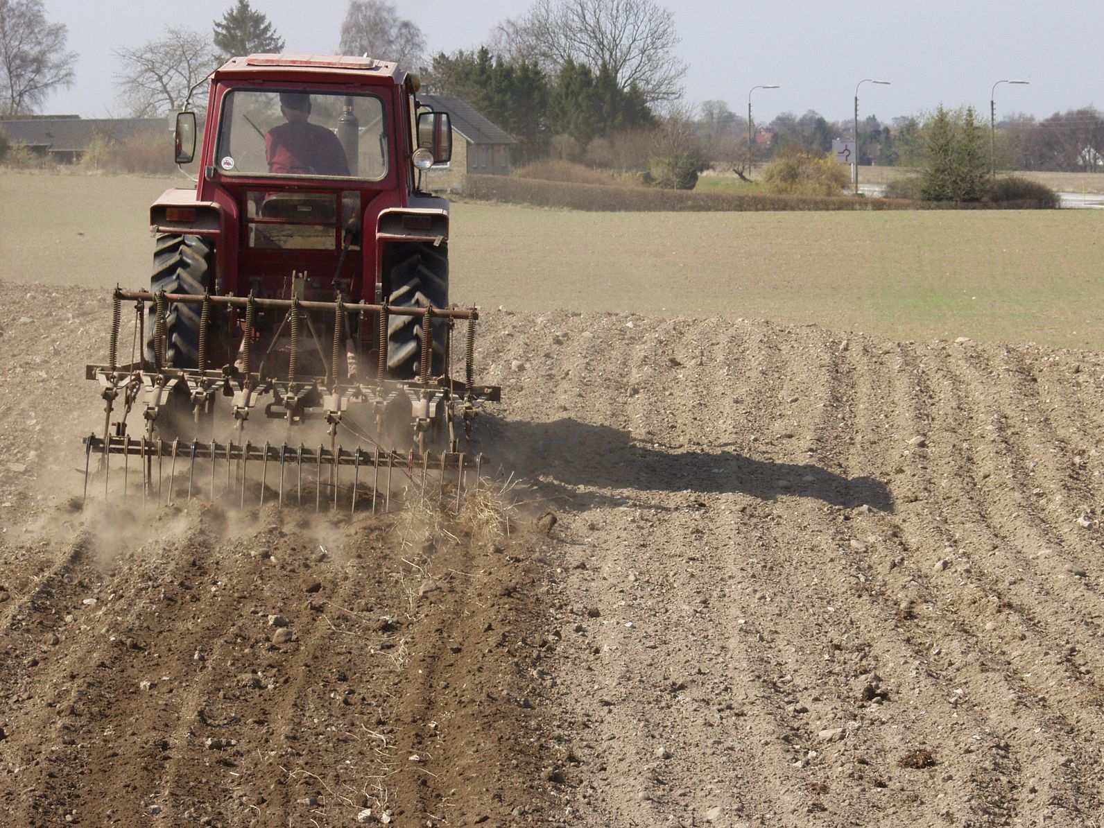 Farming vehicle rakes through a field of dirt, where soil carbon may be stored