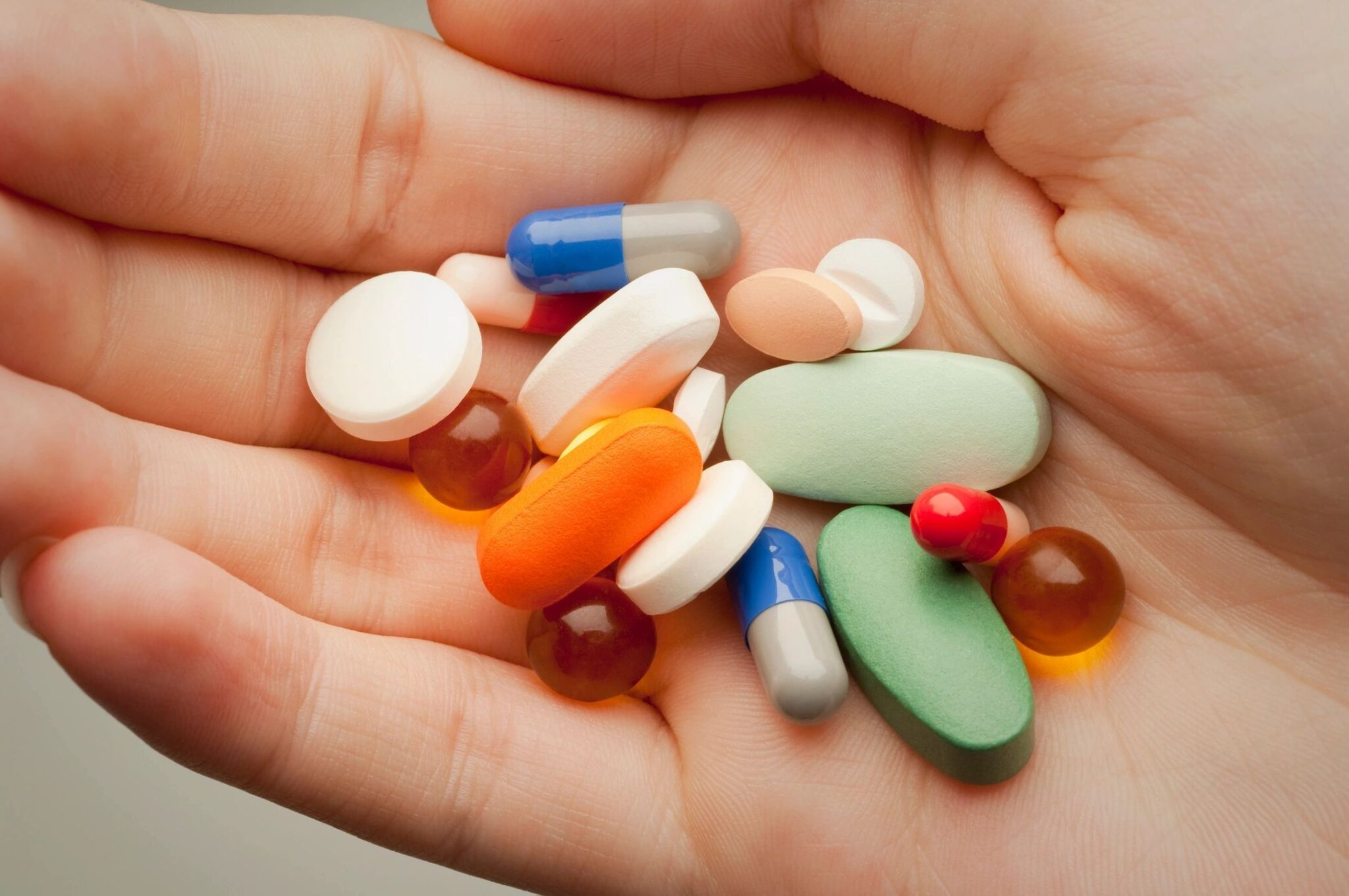 open hand holding pills of different colors and sizes, representing changes to antipsychotics drugs