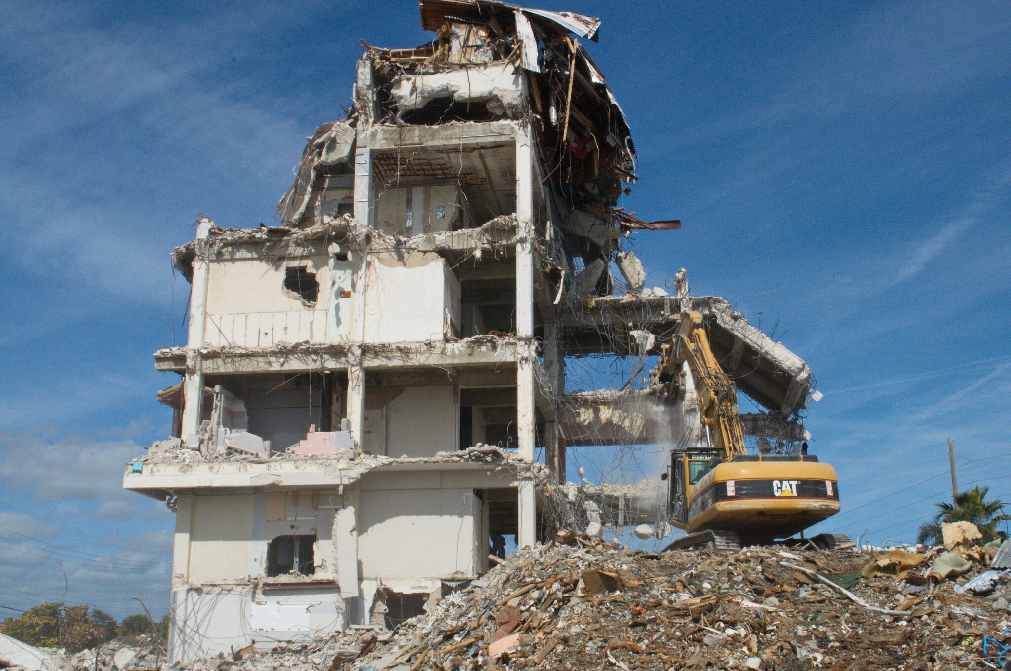 white concrete building under blue sky during daytime with demolition in progress